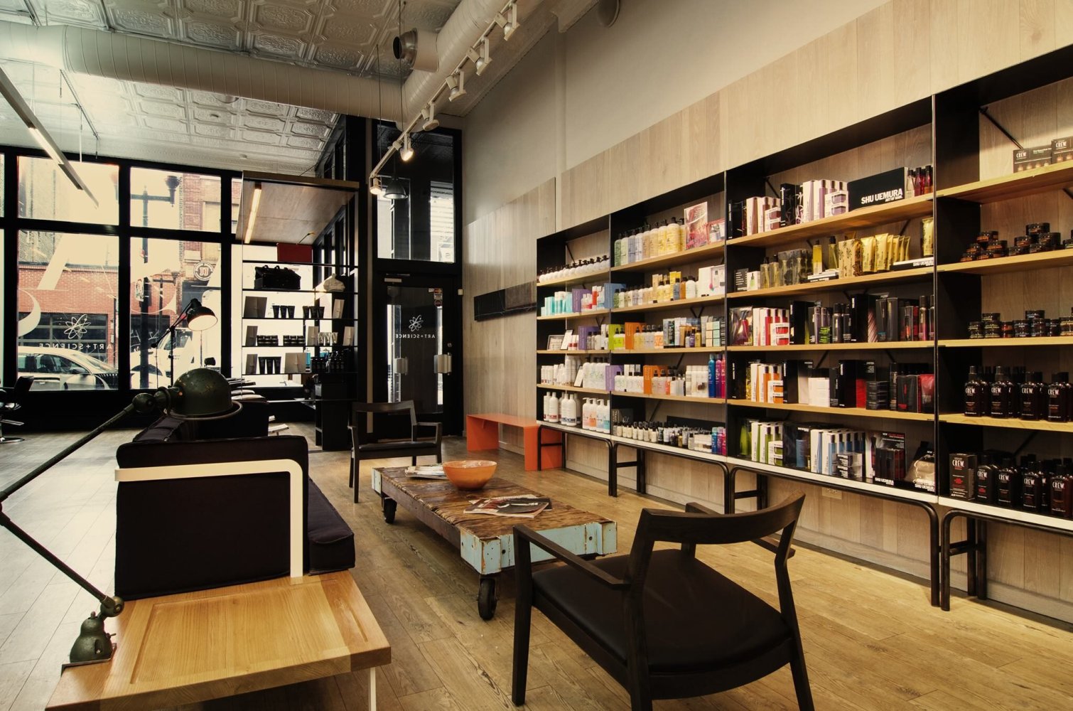 Art and Science hair salon interior with wood product shelving, lounge seating and tall storefront windows