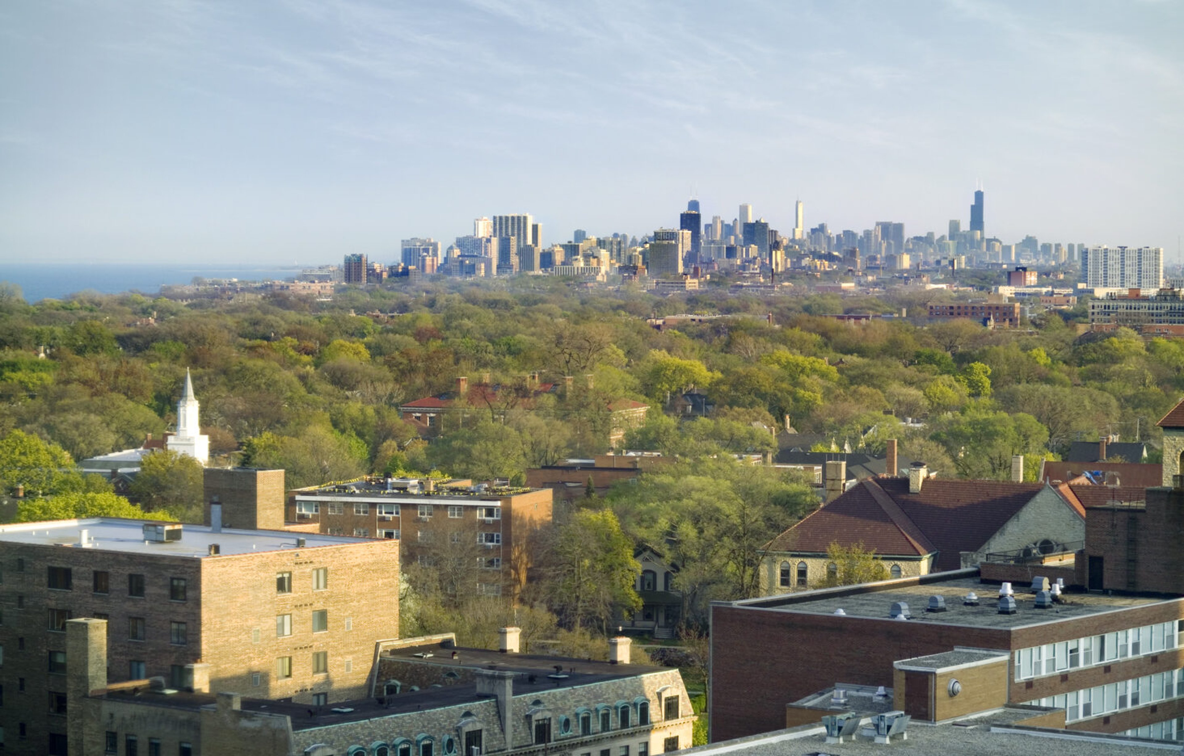 Elevated view across Evanston's leafy neighborhoods toward the Chicago skyline and the Lake Michigan shoreline