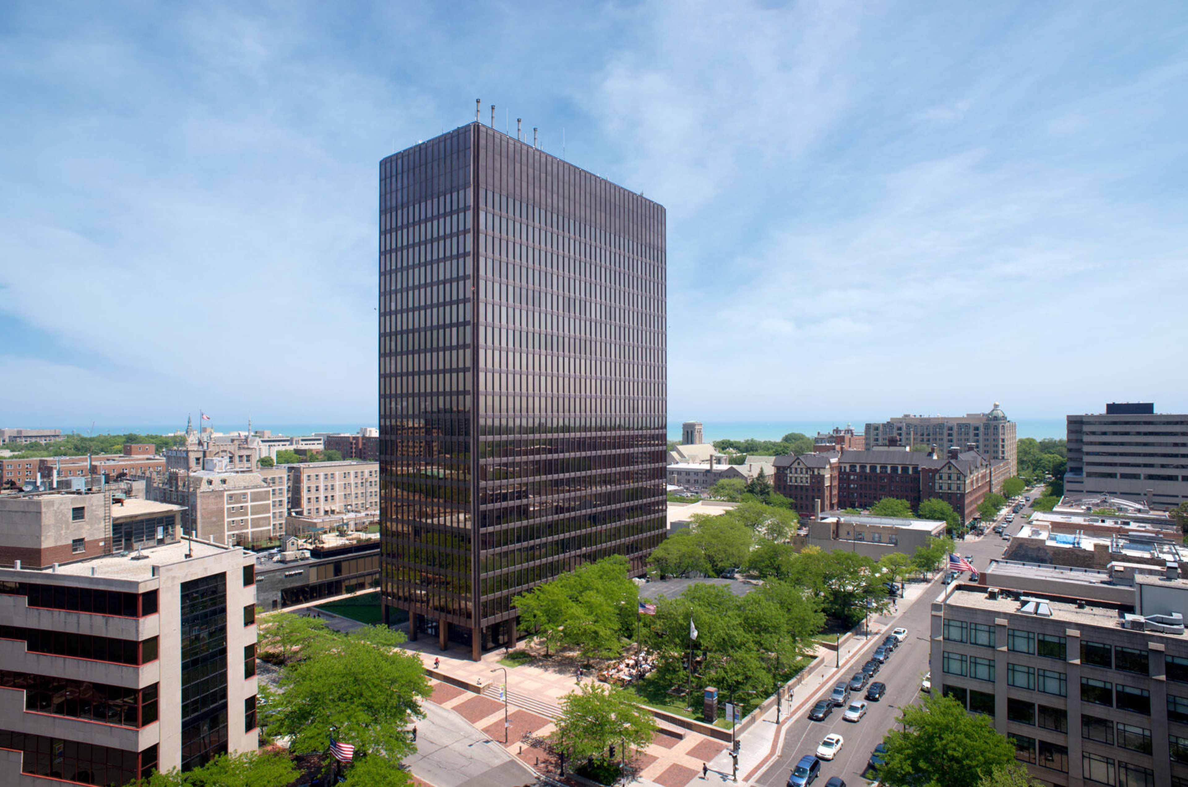 Orrington Plaza's dark bronze modernist tower rising above tree-lined downtown Evanston, with Lake Michigan on the horizon
